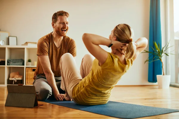 Cheerful Man Assisting His Girlfriend While She Practicing Sit Ups — Stock fotografie
