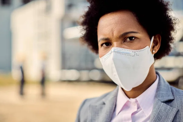 Close-up portrait of black businesswoman wearing protective face mask outdoors during COVID-19 epidemic.