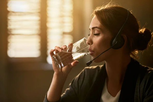 Young businesswoman drinking water with her eyes closed while taking a break in the office.