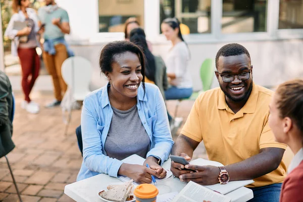 Happy African American Student Using Smart Phone While Talking Female — Fotografia de Stock