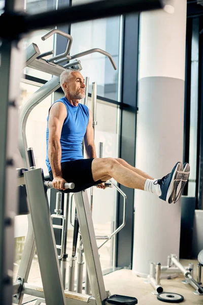 Mature Athletic Man Does Leg Raise Exercise Machine — Fotografia de Stock
