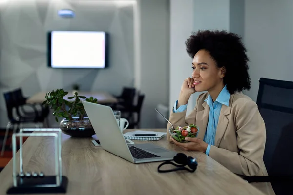 Black Female Entrepreneur Eating Salad While Using Laptop Office — ストック写真