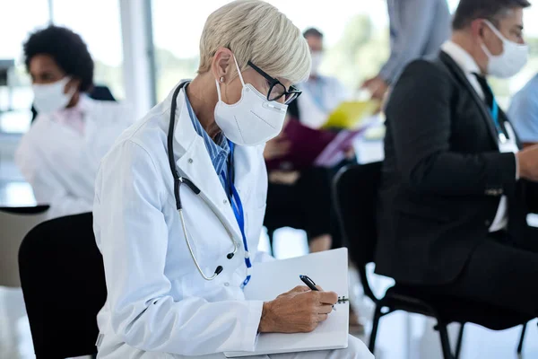 Ώριμη Υπάλληλος Υγείας Που Φοράει Προστατευτική Μάσκα Προσώπου Και Γράφει — Φωτογραφία Αρχείου