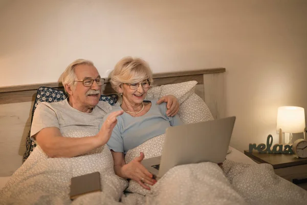 Happy Mature Couple Using Laptop Making Video Call While Lying — Photo