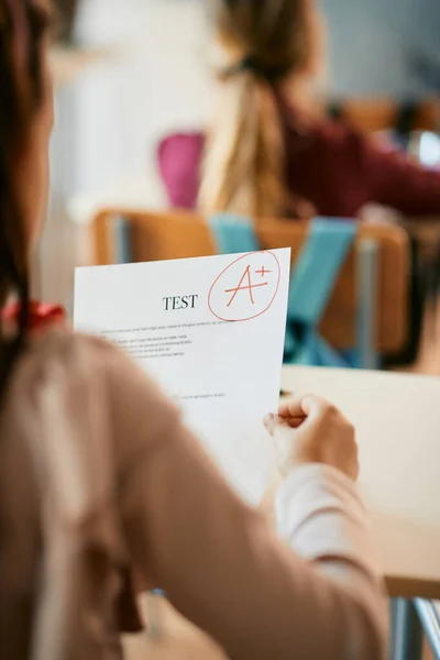 Close-up of elementary student getting A+ grade on a test at school.