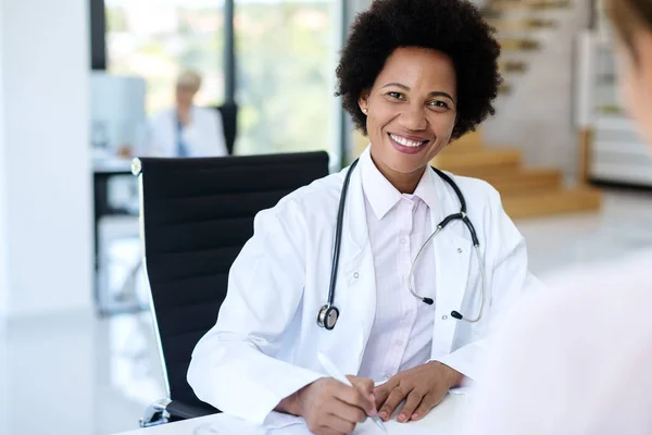 Portrait of happy black doctor working at her office and looking at camera.
