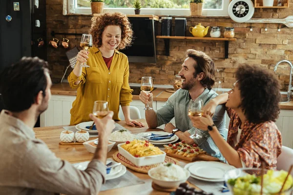 Young happy woman proposing a toast while having lunch with her fiends at home.