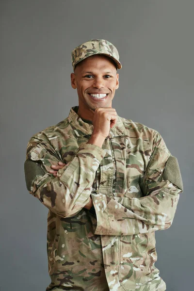 Portrait of happy African American soldier in camouflage clothing looking at camera.