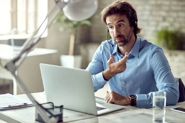 Young entrepreneur communicating with someone while having video conference in the office.