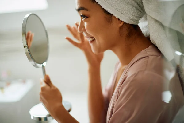 Happy Asian Woman Applying Face Cream While Looking Herself Mirror — Φωτογραφία Αρχείου