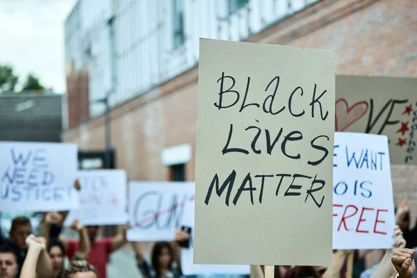 Close-up of crow of people carrying anti-racism banners on a protest for black civil rights.