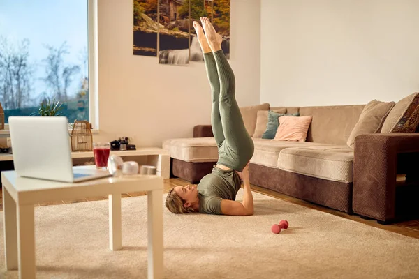 Happy Sportswoman Supporting Her Lower Back While Practicing Shoulderstand Home —  Fotos de Stock