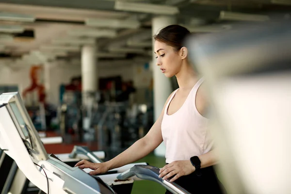 Young Female Athlete Adjusting Speed While Exercising Treadmill Gym — Stockfoto