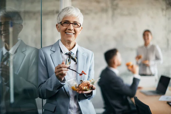 Happy Senior Businesswoman Eating Salad Lunch Break Office Looking Camera — Foto Stock