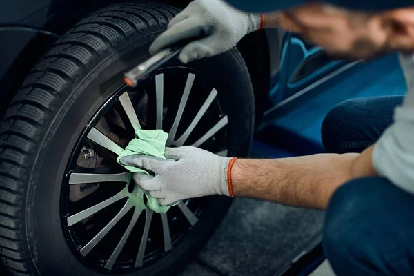 Close-up of mechanic cleaning car tire after changing it at auto repair shop.