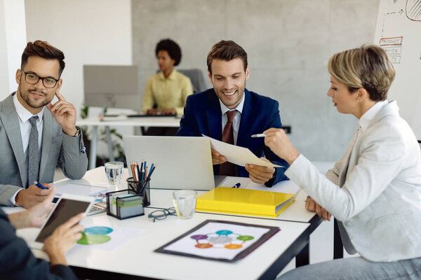 Happy businessman and his female colleague going through paperwork during a meeting in the office. 