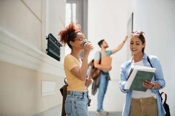Female College Students Reading Lecture Drinking Coffee While Standing Hallway — Foto Stock