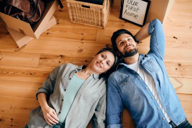 High angle view of happy couple relaxing on the floor after buying their first home.
