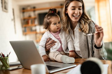 Happy working mother with her baby girl at home. 