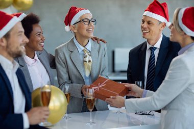 Happy mature businesswoman getting a Christmas present form her coworkers on a party in the office.