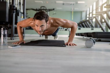 Young athletic man doing push-ups while exercising in health club. Copy space. 
