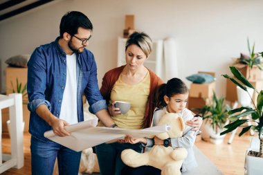 Mid adult parents and daughter feeling dissatisfied while examining housing plans of their new home. 