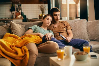 Young couple relaxing on the sofa and watching TV at home.