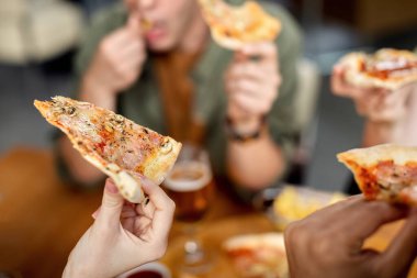 Close-up of friends having pizza for lunch in a pub. 