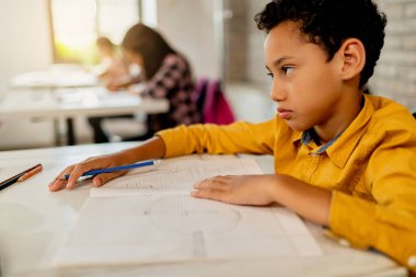 Black elementary student feeling bored during a class in the classroom. 