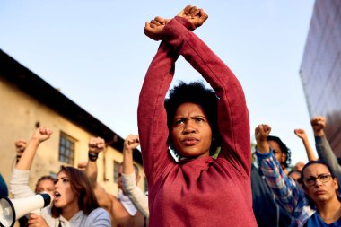 Low angle view of African American woman with arm-crossing gesture participating in a protest for human rights. 