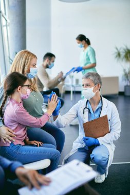 Annesiyle kliniğe gelen küçük kıza mutlu bir doktor beşlik çakıyor..