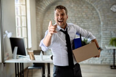 Angry businesswoman pointing at his index finger and screaming after getting fired from work. 