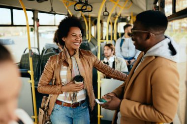 Happy black couple communicating while traveling by public transport. Focus is on woman.