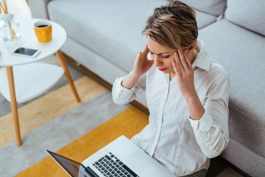 Young businesswoman having a headache while working on a computer at home. 