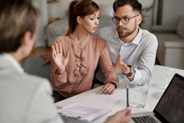 Young couple talking to their real estate agent on a meeting. 