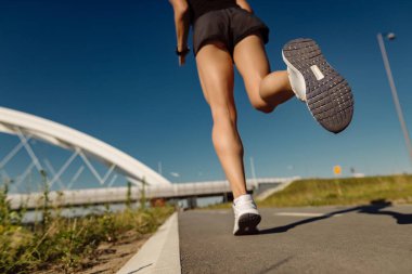 Low angle view of female runner jogging outdoors. Copy space. 