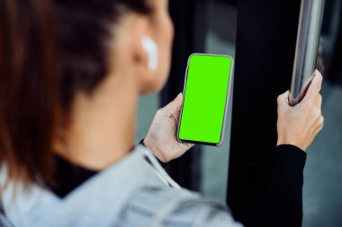 Close-up of athletic woman using smart phone while coming to gym for sports training. Copy space. 