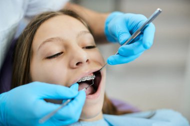 Close-up of dentist examining dental braces of small girl at dental clinic.  