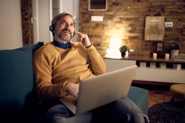 Businessman using laptop and talking while having conference call in the evening at home. 