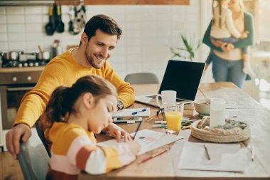 Happy father working at home and communicating with his daughter who is drawing on the paper. 