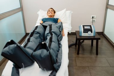 Young happy woman having pressotherapy treatment in spa center. 