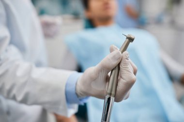 Close-up of stomatologist using dental drill while working with patients at dentist's office.