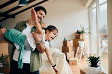 Happy little girl having fun with her father while moving into new home. 