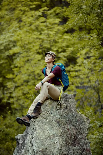 Smiling Female Backpacker Resting Mountain Rock While Taking Break Hiking — стоковое фото