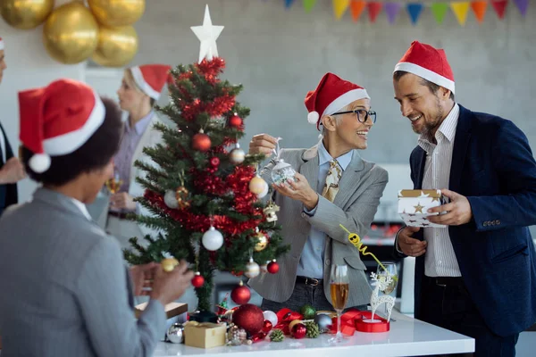 Happy Mature Businesswoman Communicating Male Colleague While Decorating Christmas Tree — ストック写真