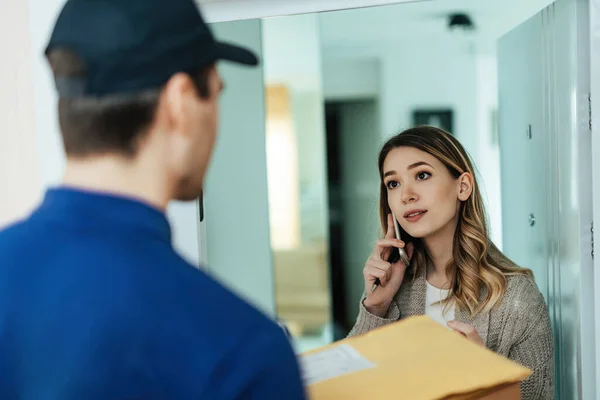 Young Woman Communicating Mobile Phone While Receiving Package Courier Home — Stok Foto