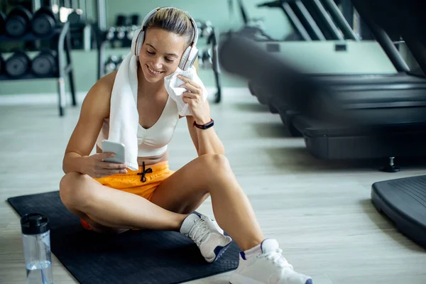 Happy Female Athlete Texting Mobile Phone While Relaxing Floor Gym — Stockfoto