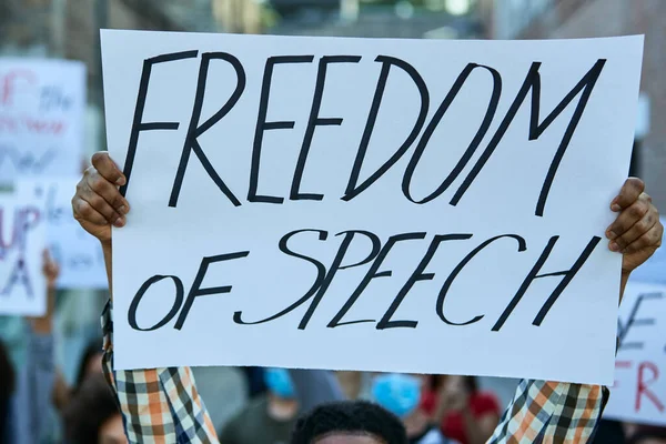 Close-up of man participating in protest for human rights and carrying banner with \'freedom of speech\' inscription.