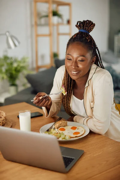 Happy Black Woman Eating Breakfast While Making Video Call Laptop — Stockfoto