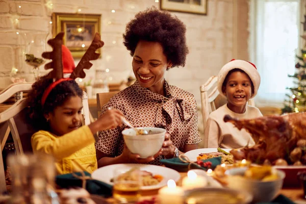 Happy African American mother enjoying in family meal with her kids on Christmas.